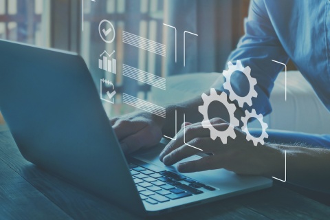 Hands typing on a laptop with icons of gears and checkboxes overlaid on the image.