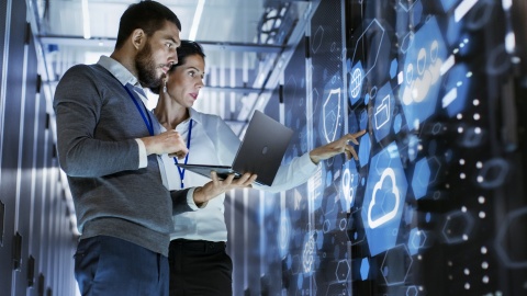 man and woman looking at computer server