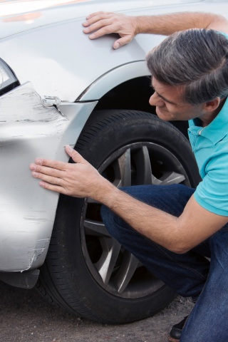 man looking at dent in car