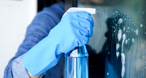 gloved hand spraying glass cleaner