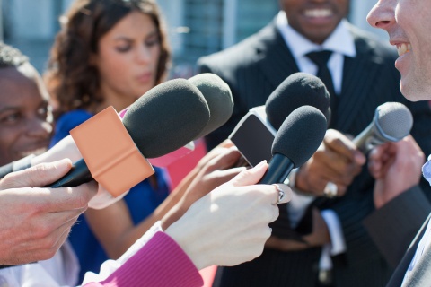 media with microphones surrounding speaker
